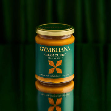 Jar of Gymkhana Goan Curry cooking sauce on a green background